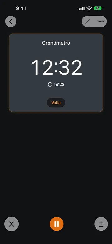 Um Cronômetro em execução marcando 12:32, com o horário de início 18:22 abaixo da leitura e um botão Volta. Na parte inferior da tela há um botão X, um botão laranja de Pausar e um botão de mais ou menos.